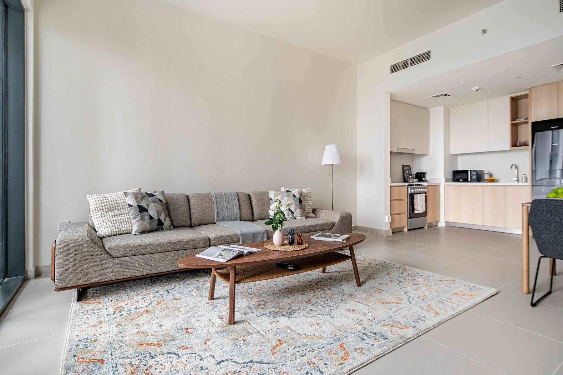 A bright living room with a sofa and an open kitchen.