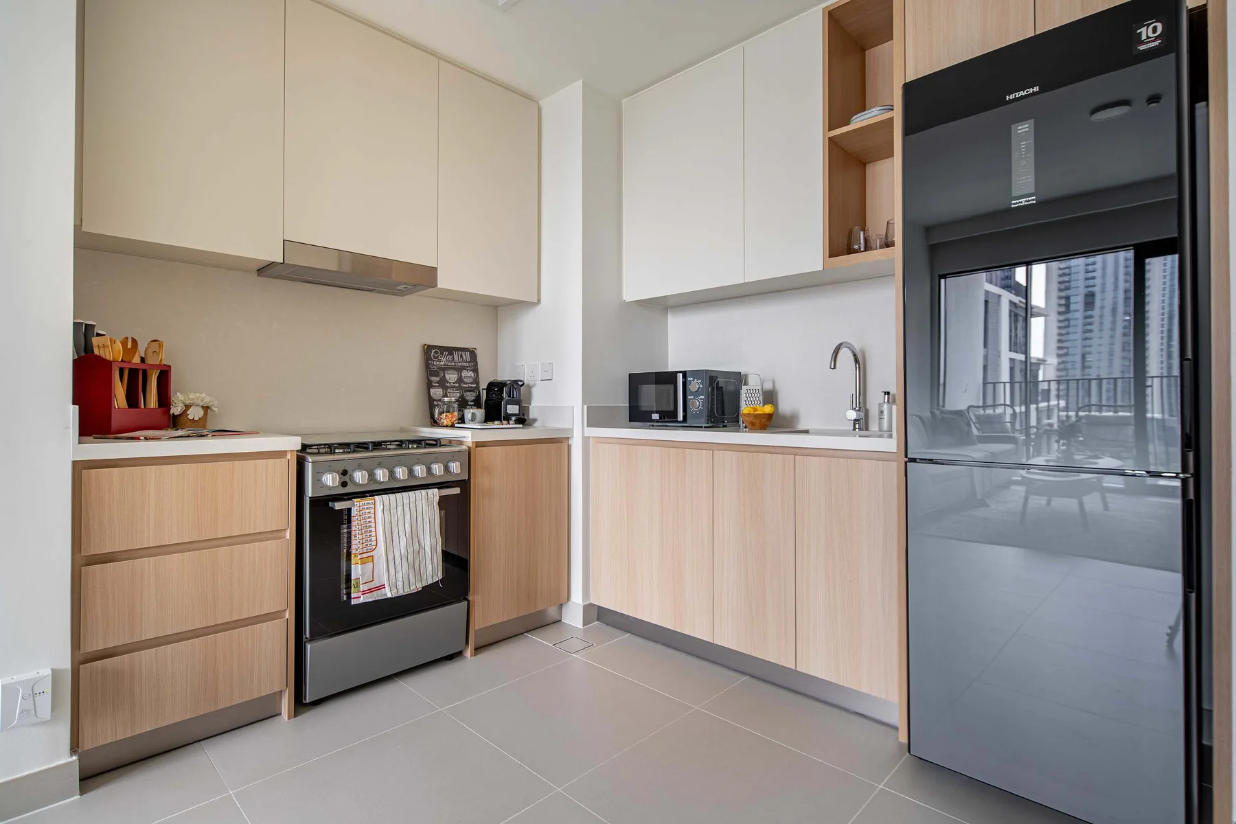 A modern kitchen with light cabinetry, a cooktop, and a refrigerator.