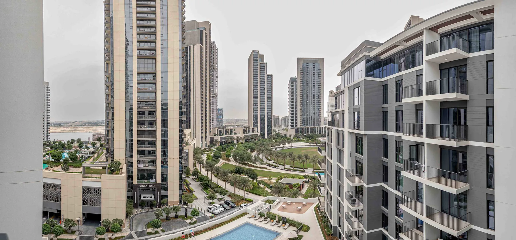 A modern residential complex with high-rise buildings, landscaped grounds, and a swimming pool.