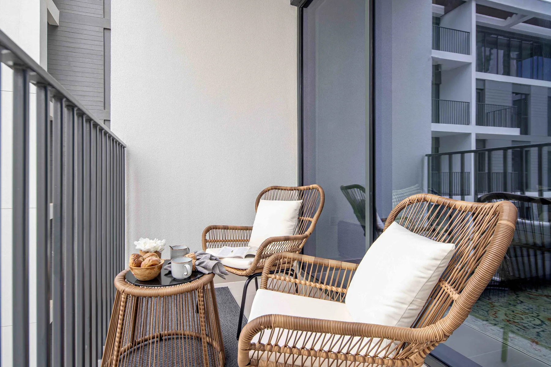 A balcony seating area with woven chairs and a small table.