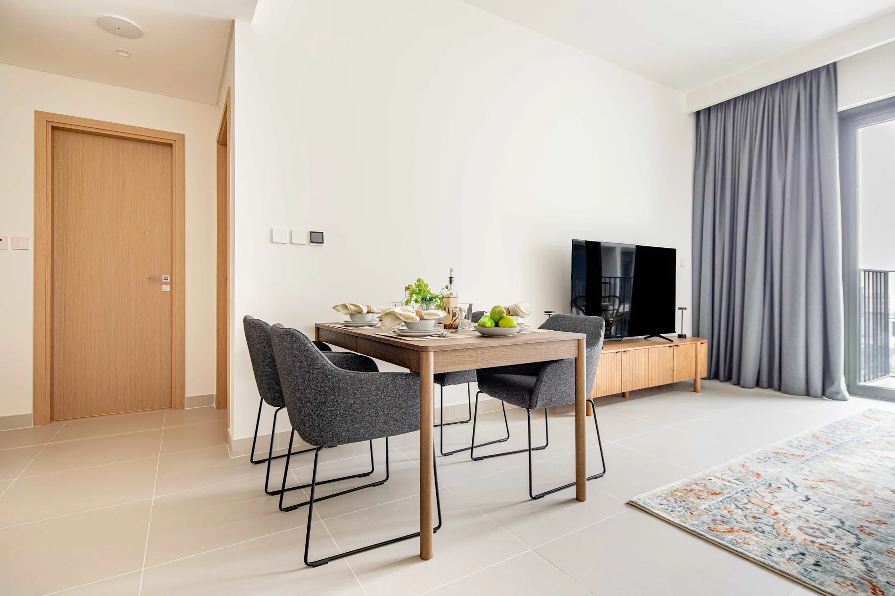A dining area with a table and chairs beside a television and large window.