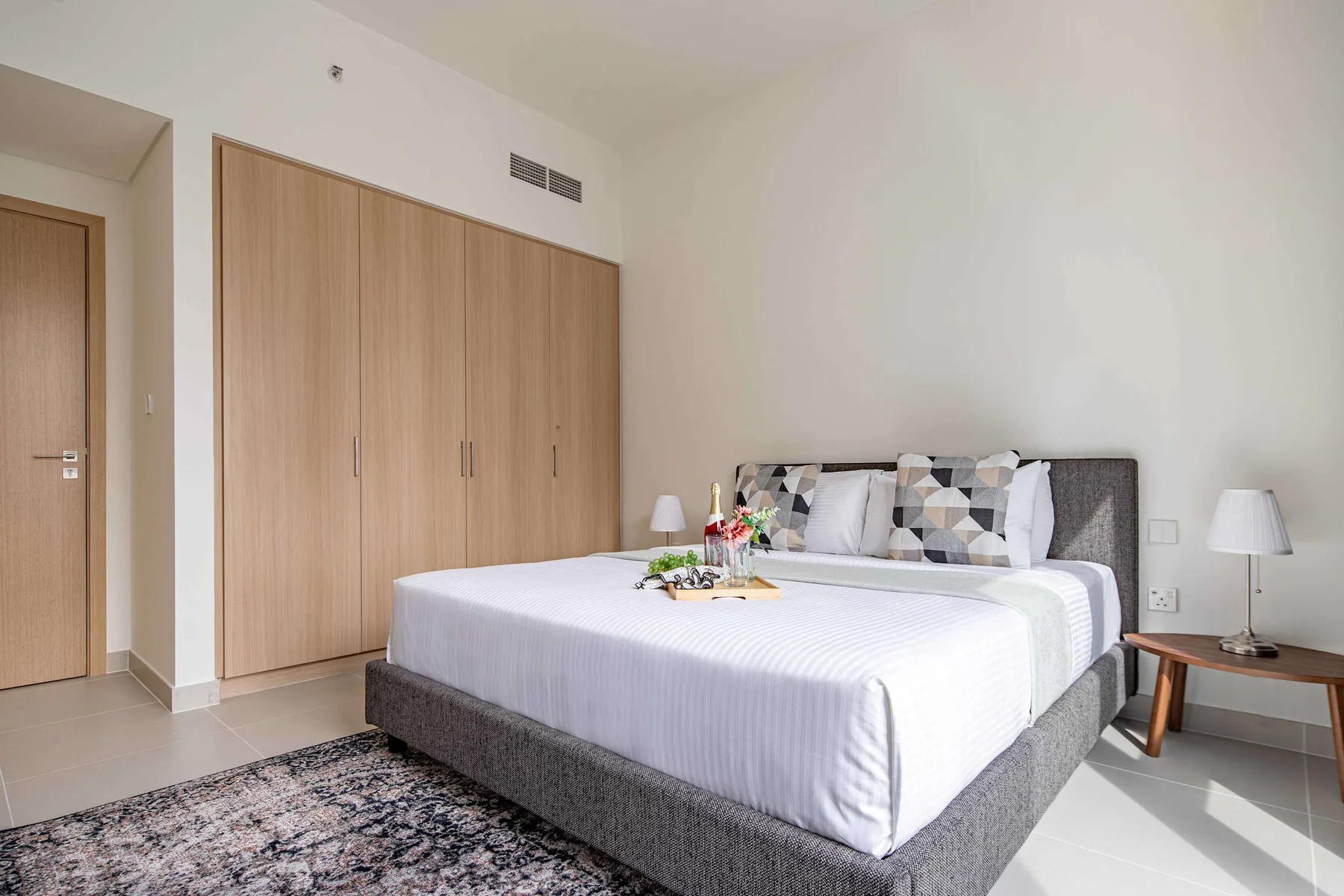 A bedroom with a neatly made bed and light wood wardrobes.