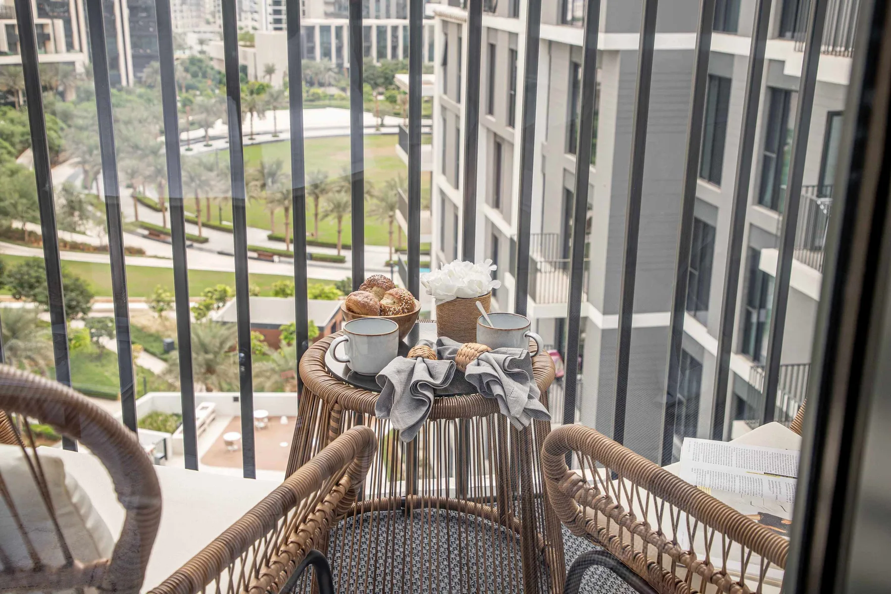 A balcony seating area overlooks landscaped grounds and nearby buildings.