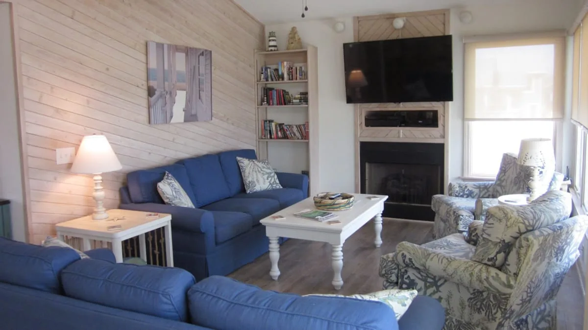 A living room with blue seating, a fireplace, and a television.