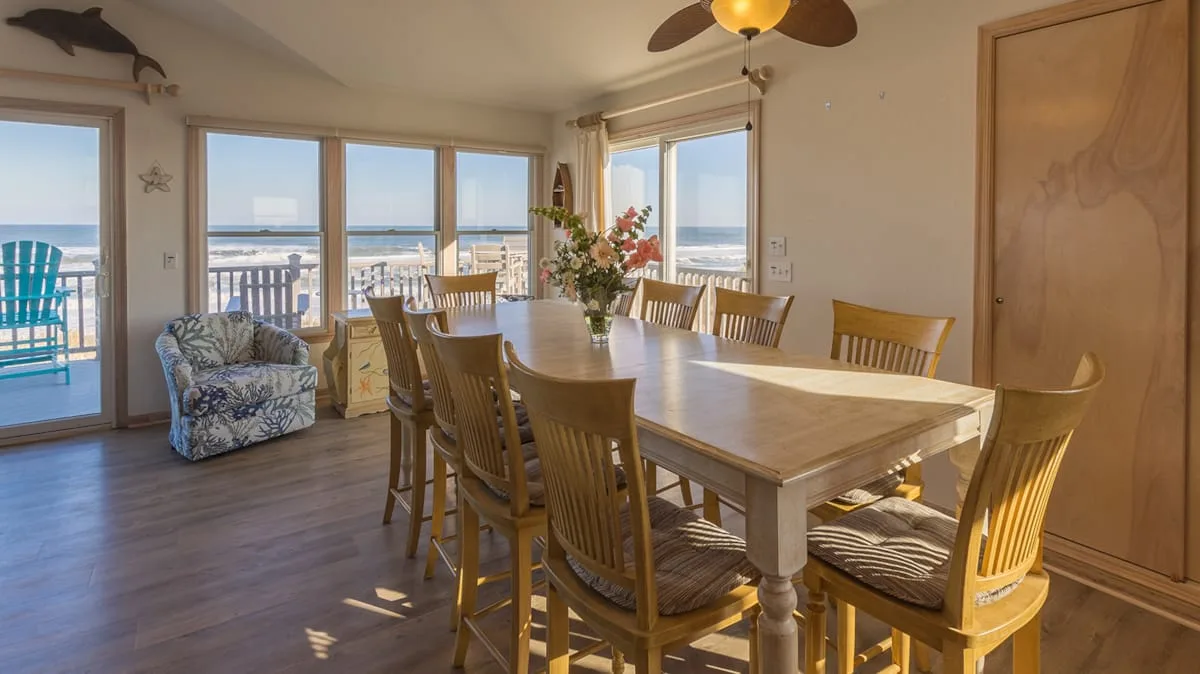 Un comedor luminoso con una mesa de madera y amplias ventanas con vistas al agua.