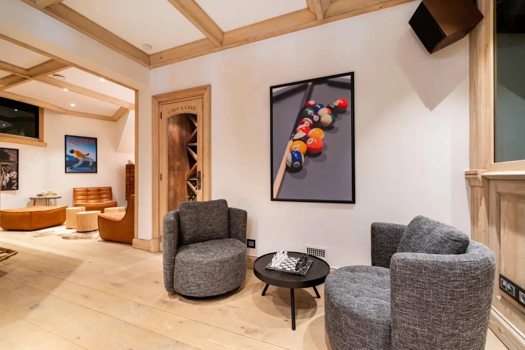 Cozy room with two gray chairs, a round table, and a billiards-themed wall art. Warm lighting and wooden accents create a welcoming atmosphere.