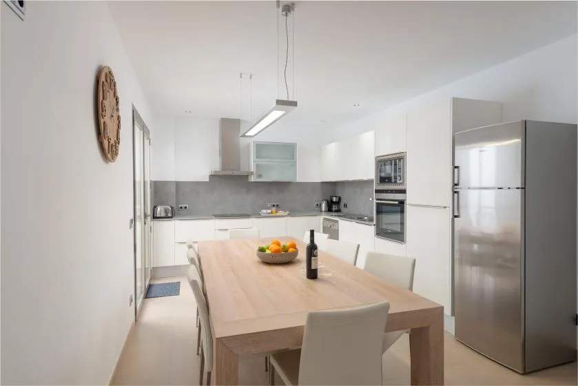 Una cocina moderna y luminosa con mesa de comedor y electrodomésticos de acero inoxidable.