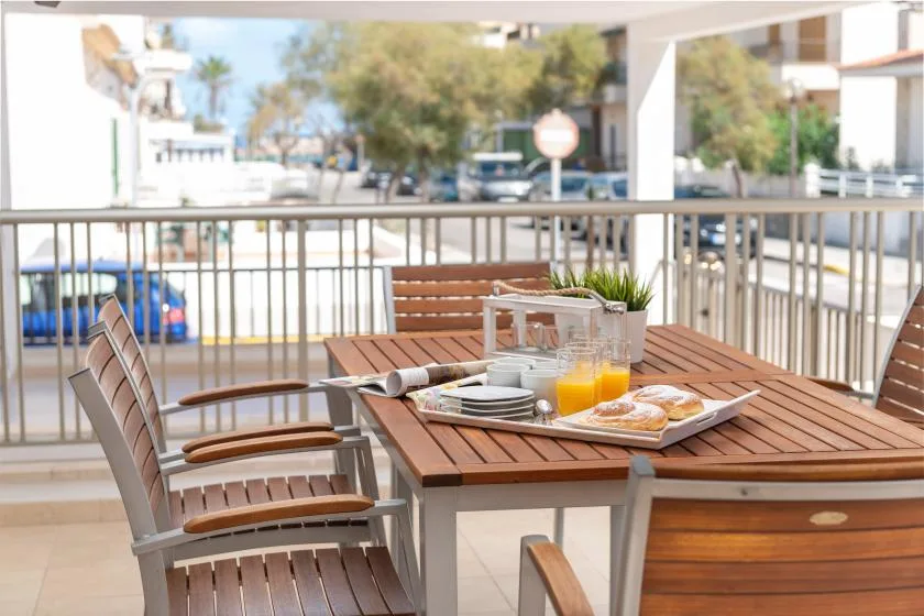 Una mesa de comedor al aire libre está puesta con platos y bebidas junto a asientos de patio.