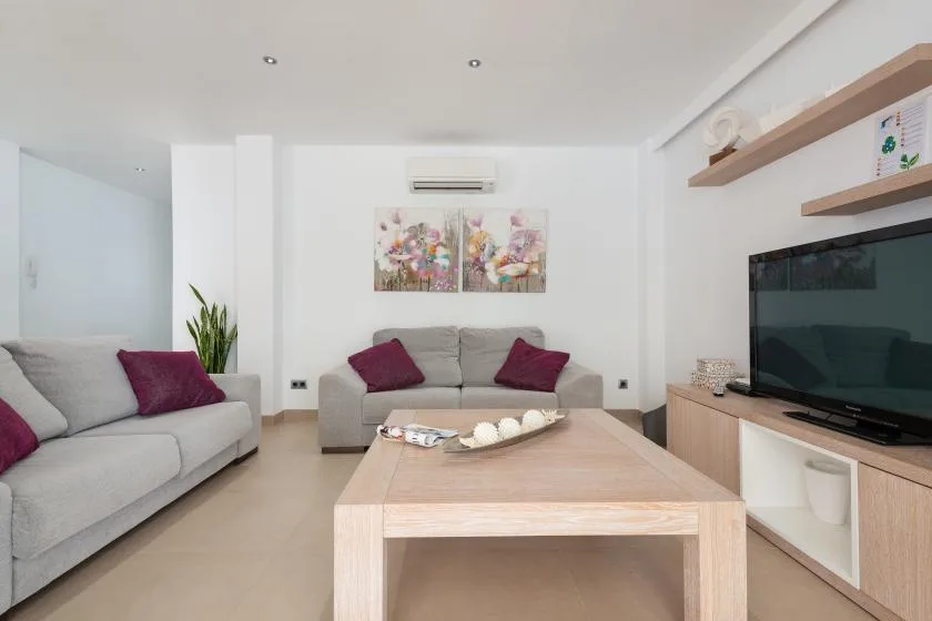 Una sala luminosa con asientos, una mesa de centro y un televisor.