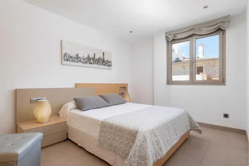 Un dormitorio con una cama doble, mesillas de noche y una ventana.
