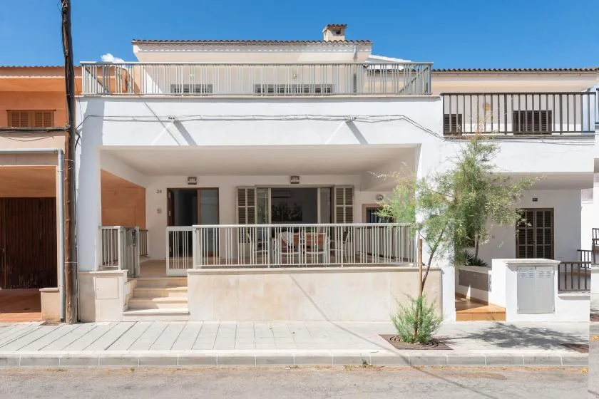 Un edificio blanco de varias plantas con un balcón cubierto y una terraza en la azotea.