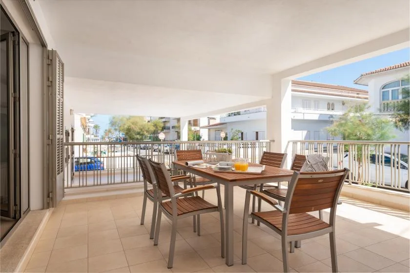 Comedor exterior cubierto con una mesa y sillas, con edificios cercanos a la vista.