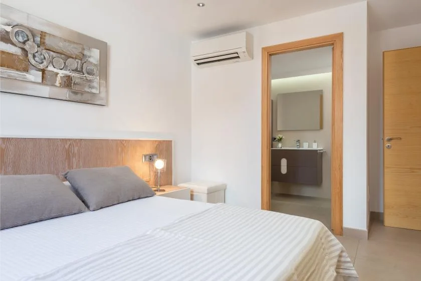 Dormitorio con una cama y una puerta abierta a un baño.