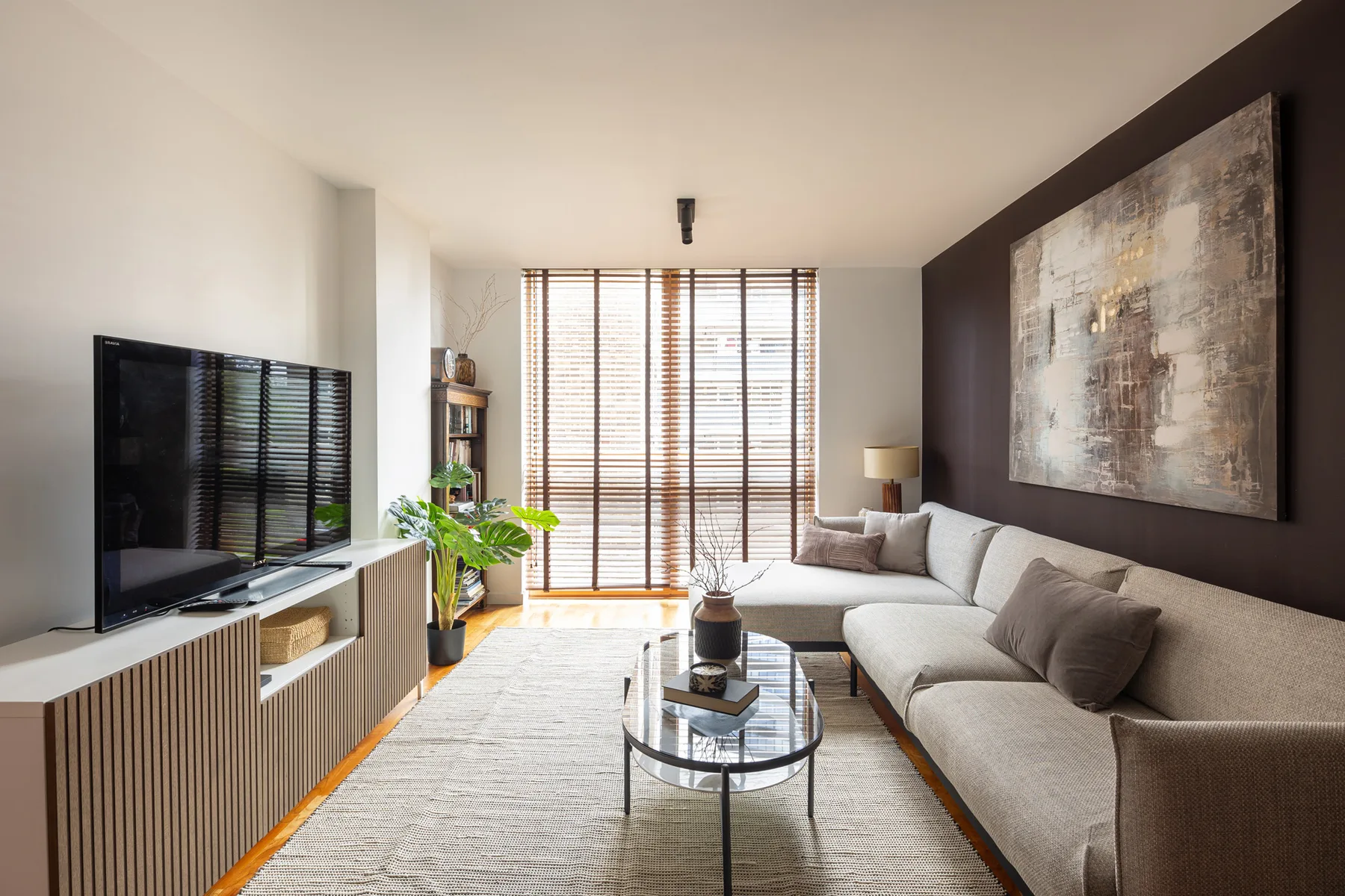 Una sala de estar con asientos seccionales, una mesa de centro de vidrio y grandes ventanas.