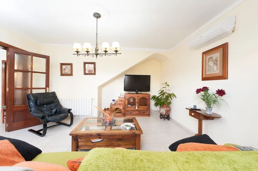 A bright living room with seating, a wooden coffee table, and a television.