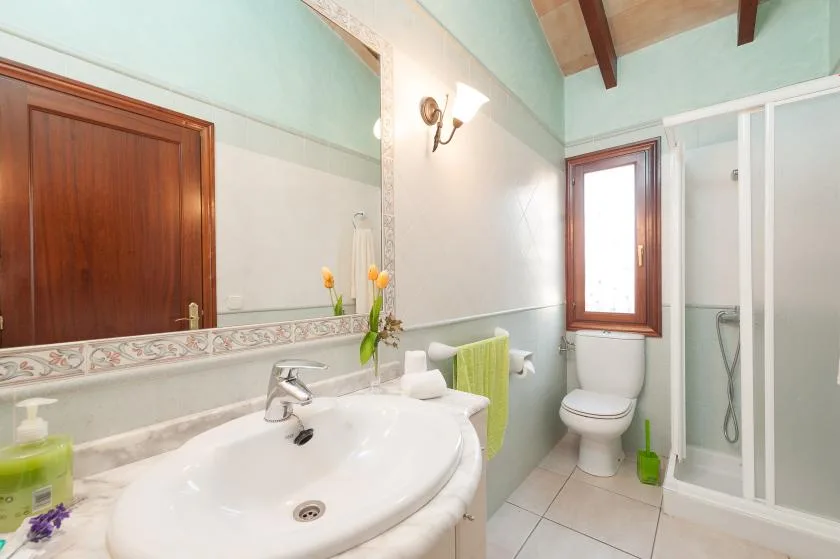 A tiled bathroom with a sink, toilet, and glass shower enclosure.