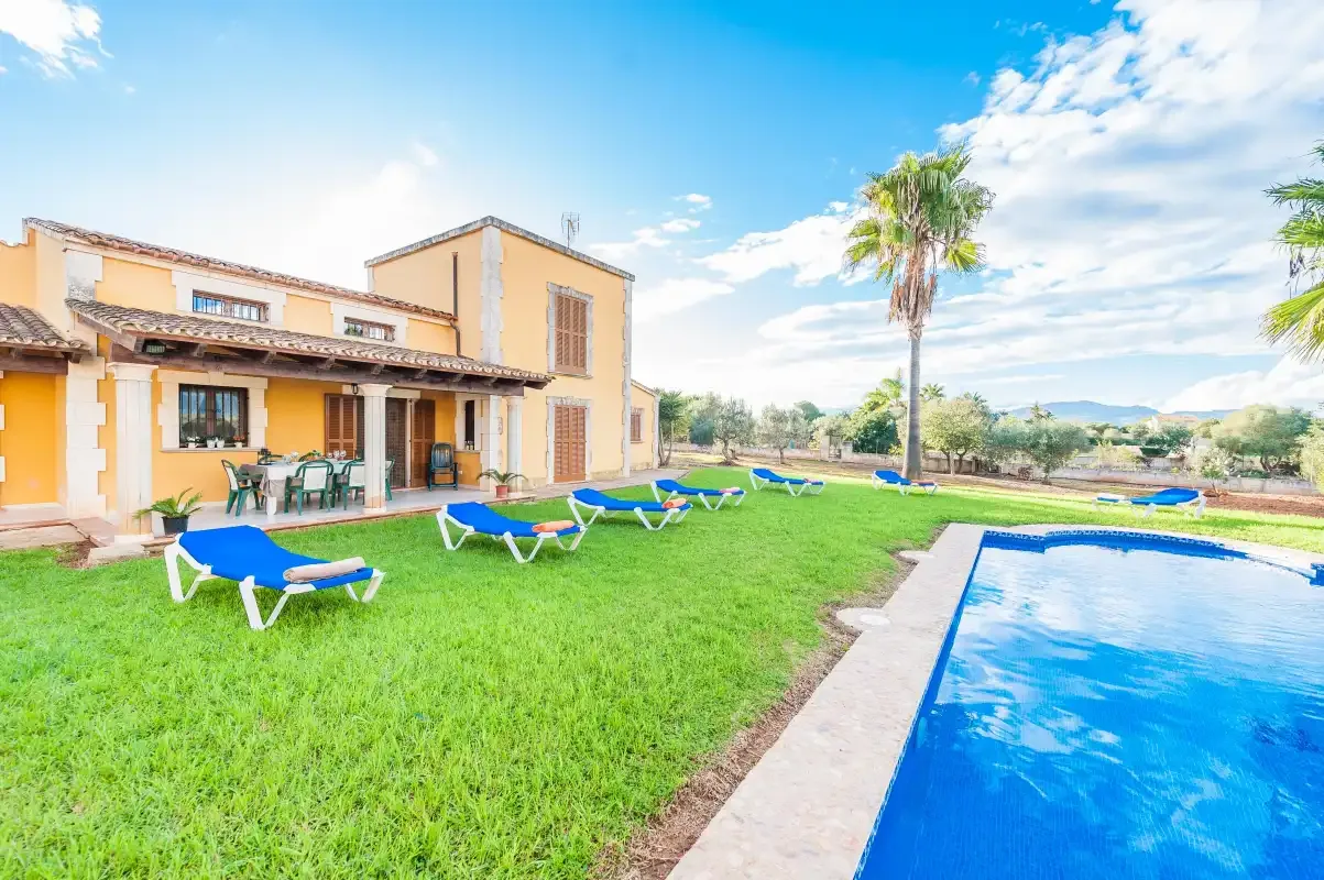 A villa, lawn, and swimming pool are visible beneath a bright blue sky.