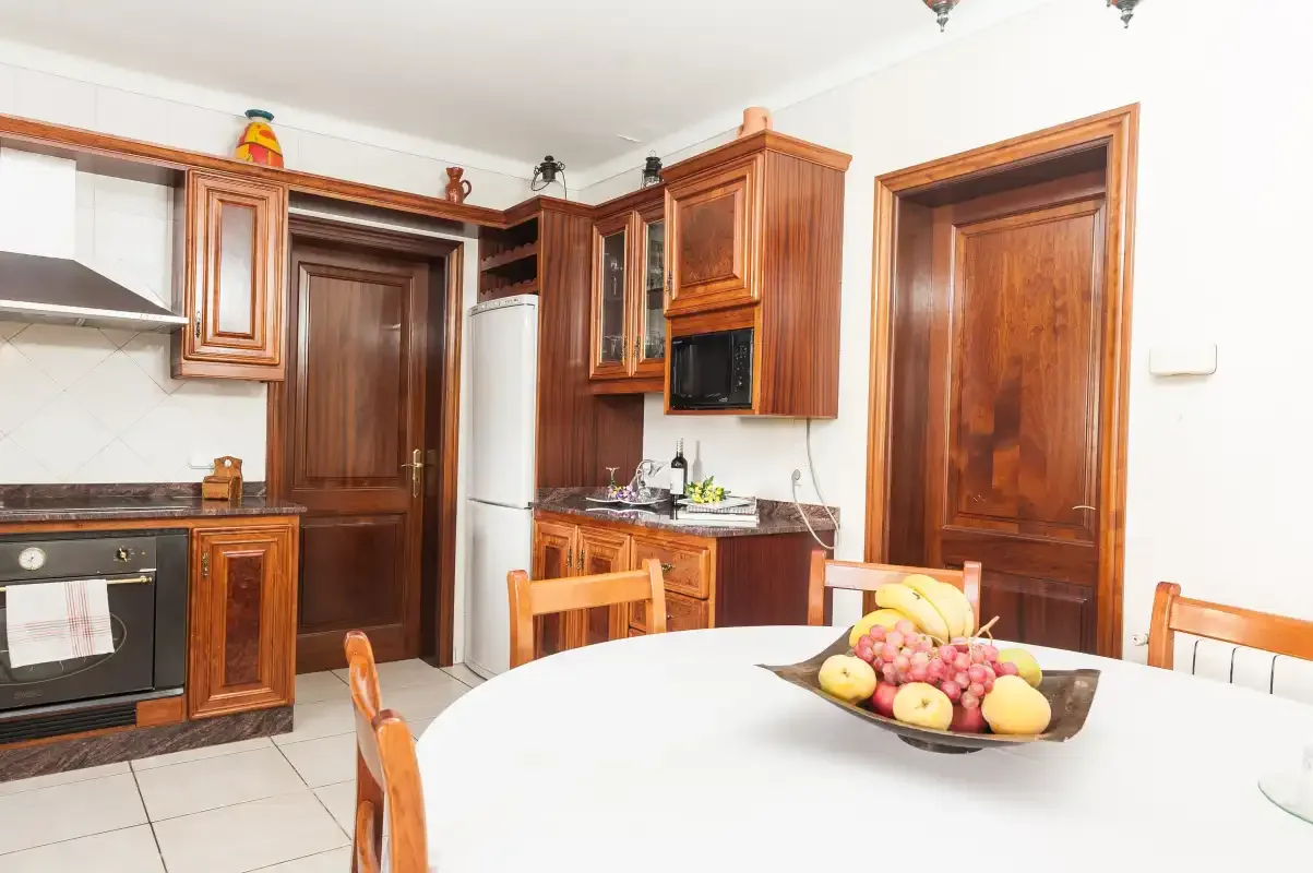 A kitchen and dining area with wooden cabinets and a table set with fruit.