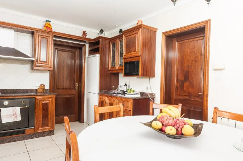 A kitchen with wooden cabinets and a fruit bowl on the table.