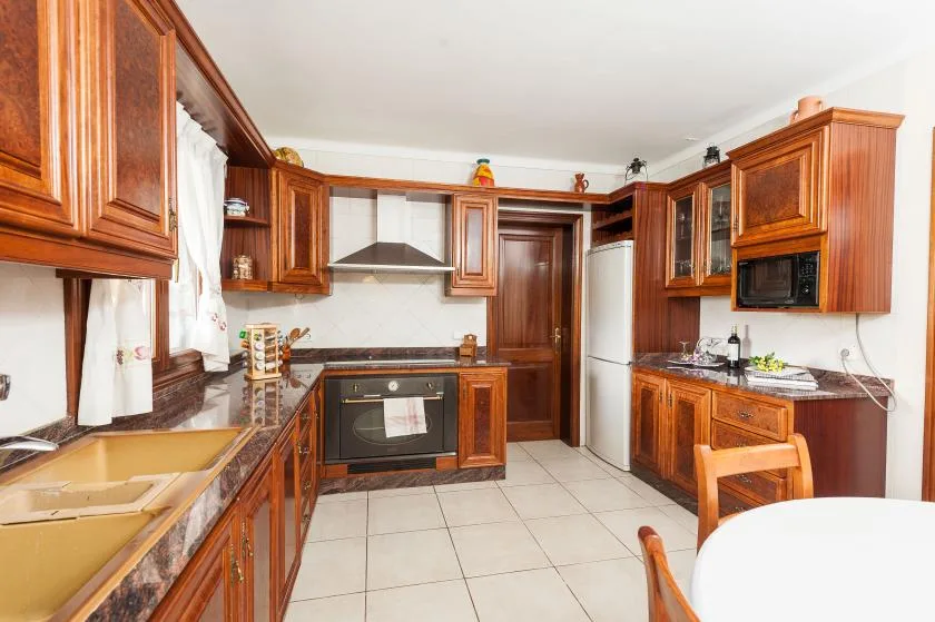 A kitchen with wooden cabinets, a built-in oven, and a central doorway.