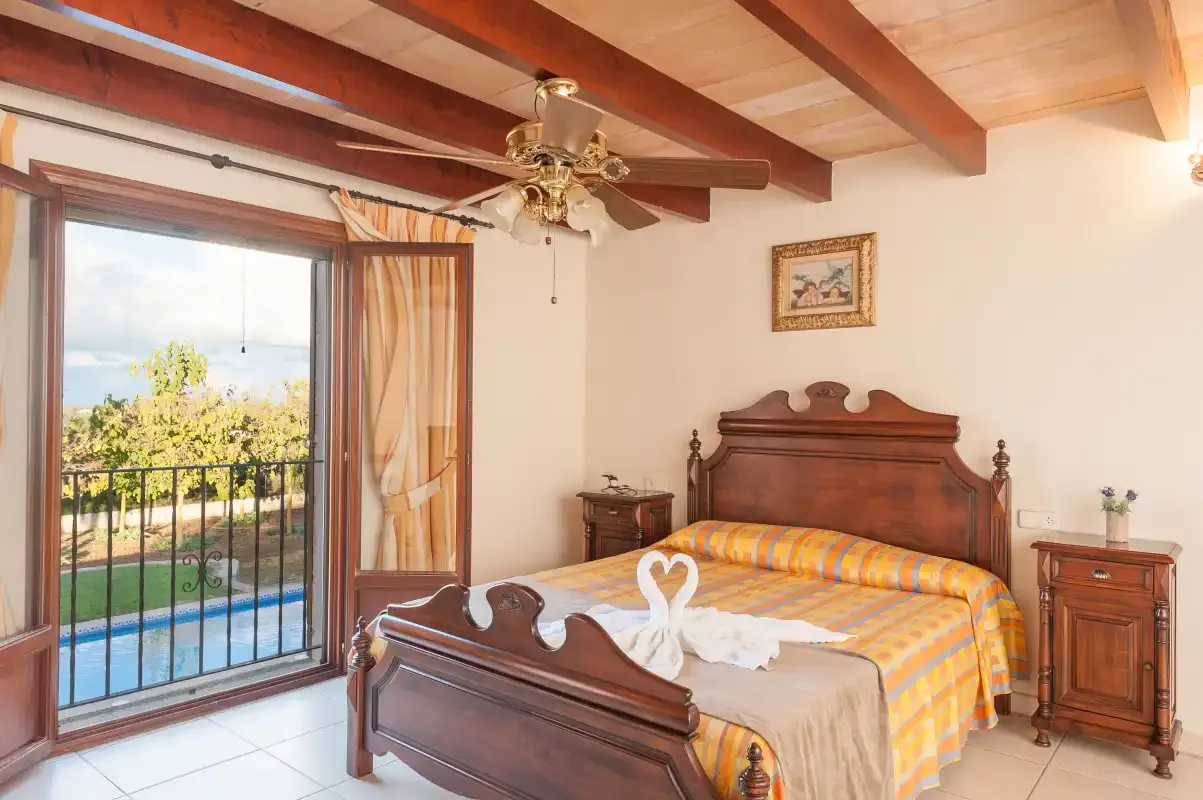 A bedroom with a wooden bed and sliding glass doors opening onto a balcony.