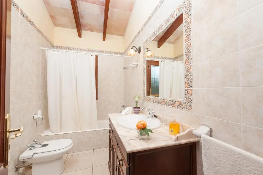 A tiled bathroom with a vanity, large mirror, and shower curtain.