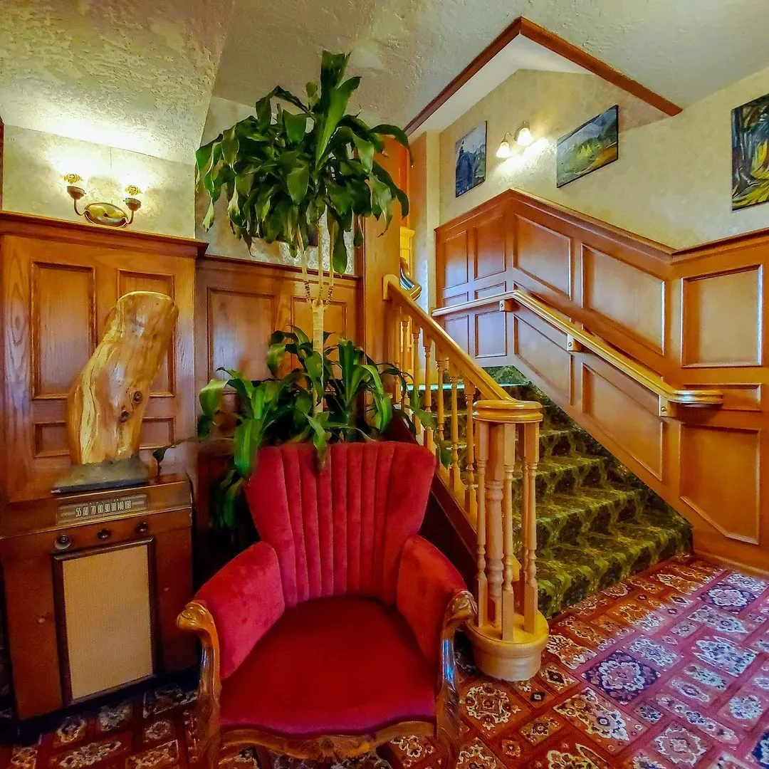 Una silla roja en una sala con escaleras y una planta