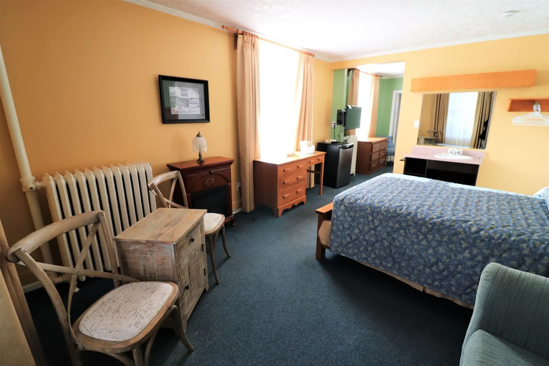 Una habitación de hotel con una cama, sillas y un radiador