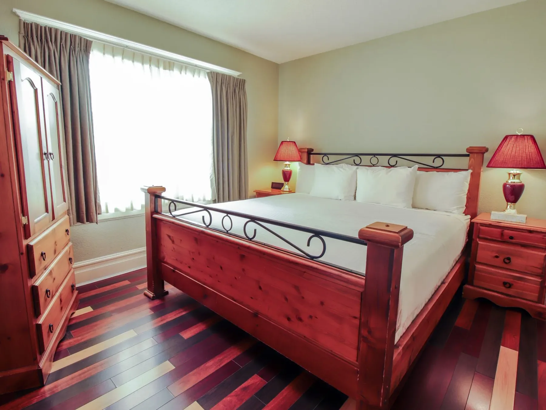 Un dormitorio con una cama king size, mesas de noche, una cómoda y una ventana