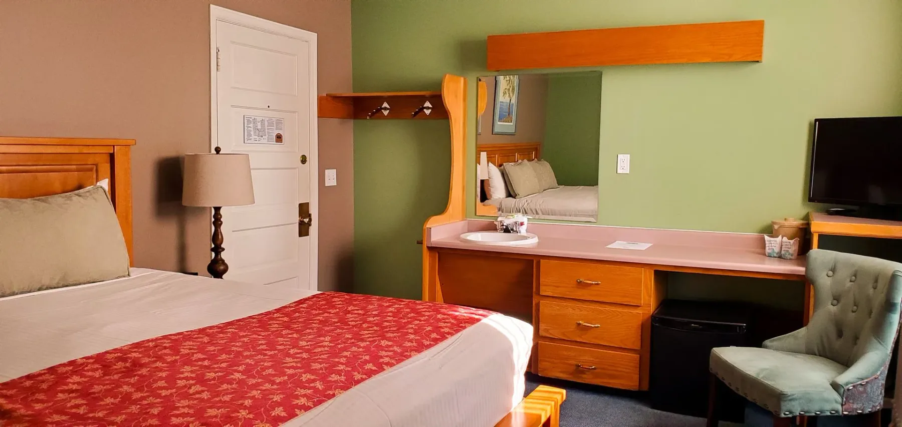 Una habitación de hotel con una cama king size, un escritorio, una silla y un televisor