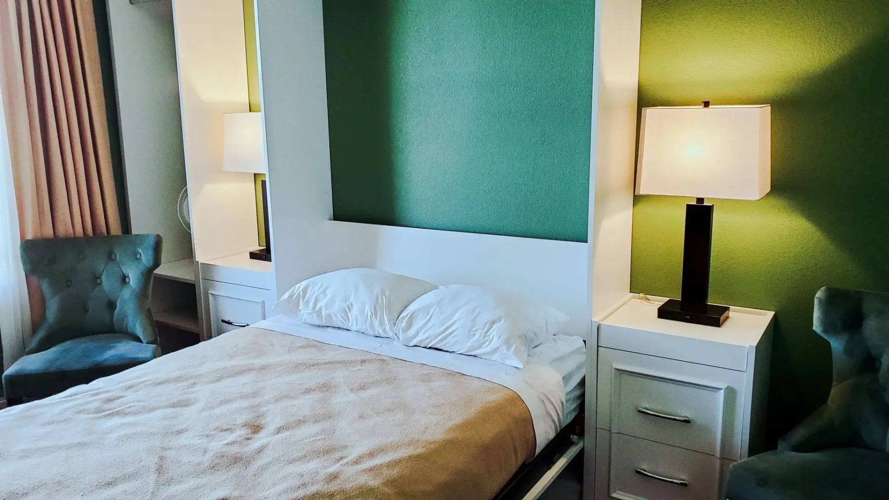 Una habitación de hotel con una cama, una silla, una mesa de noche y una lámpara