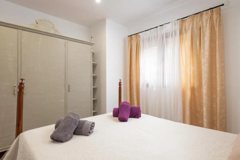 Un dormitorio con una cama tendida y una ventana grande con cortinas.