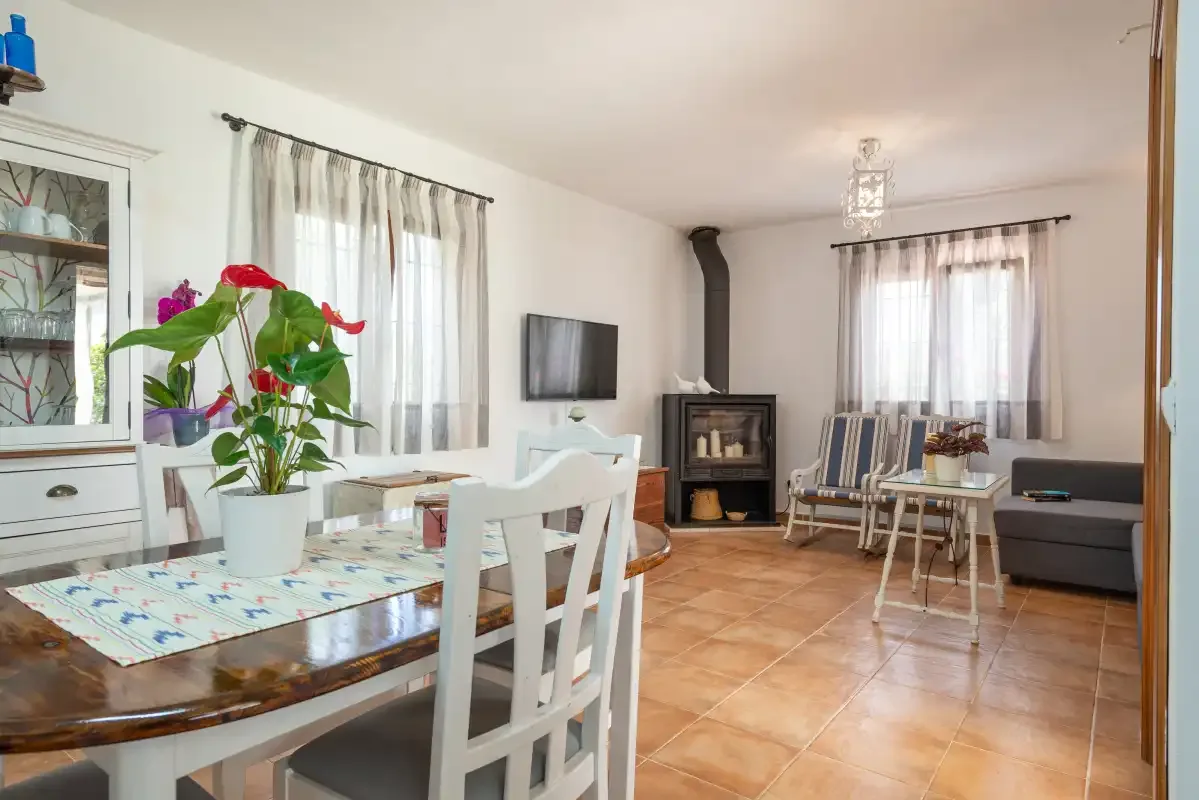 Salón-comedor amueblado con una estufa de leña y ventanas amplias.