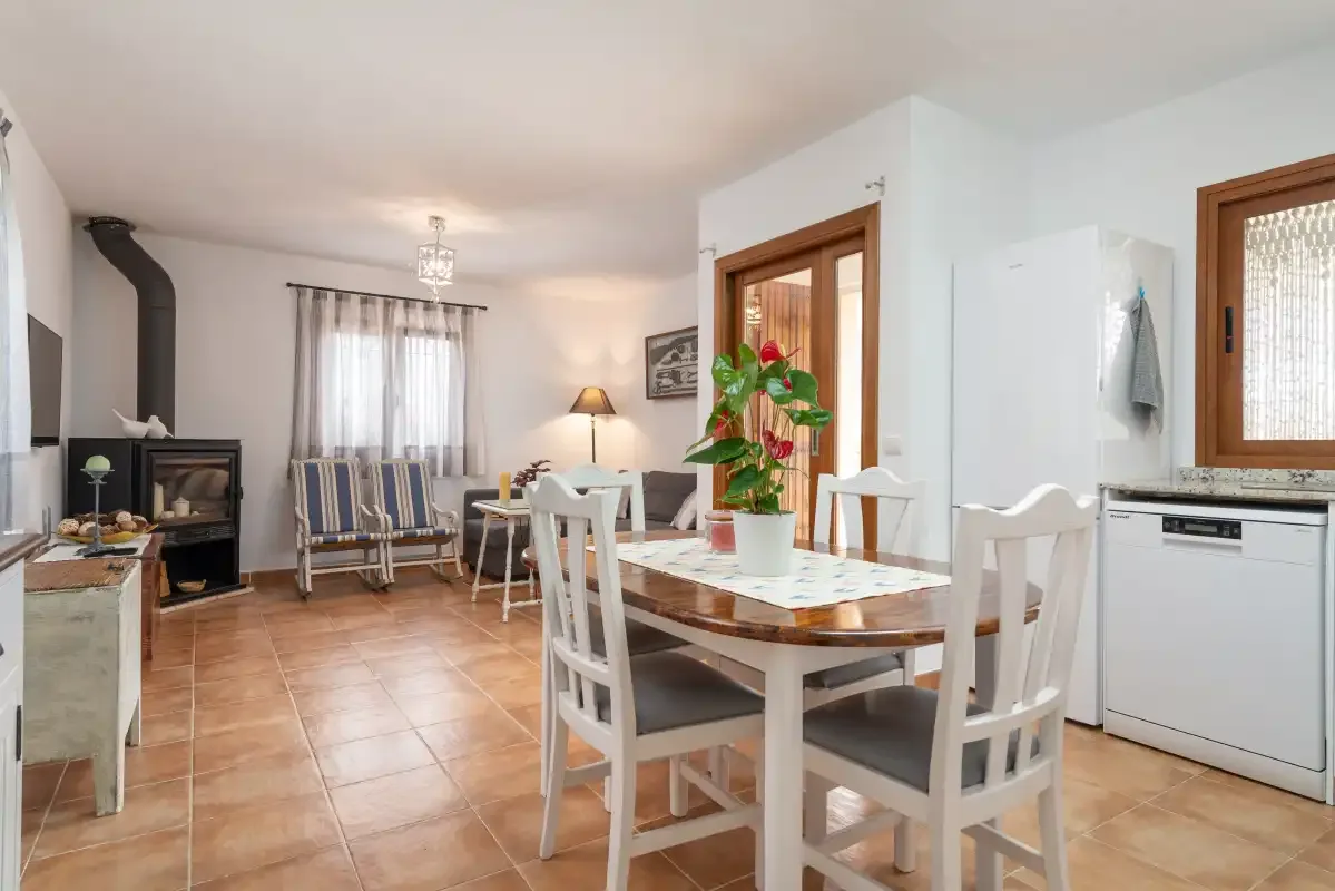 Un comedor con mesa de madera y sillas junto a una zona de estar.