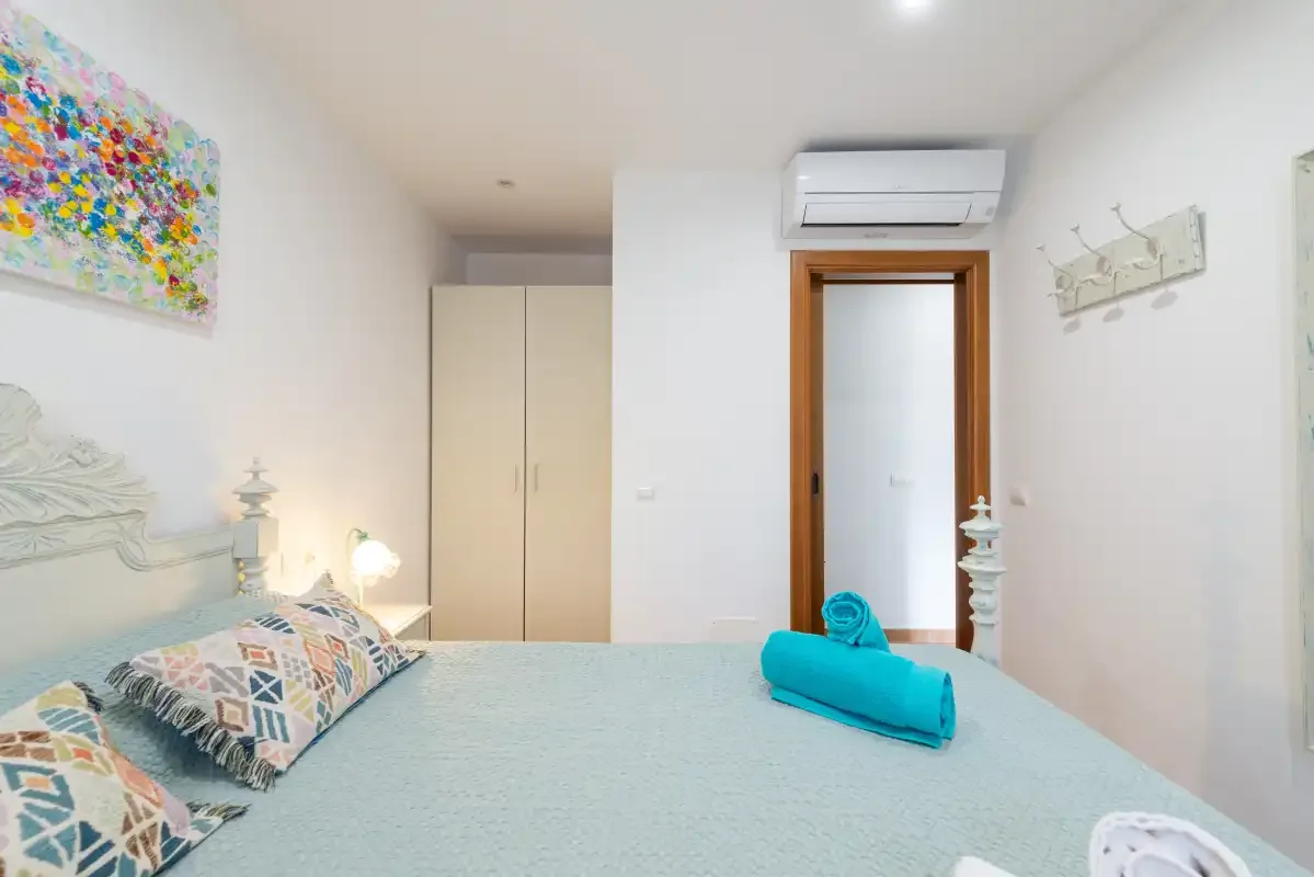 Un dormitorio con una cama bien hecha y una toalla turquesa.