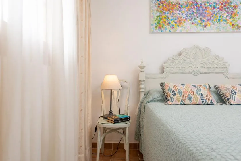Un dormitorio con una colcha estampada y una lámpara junto a la cama.