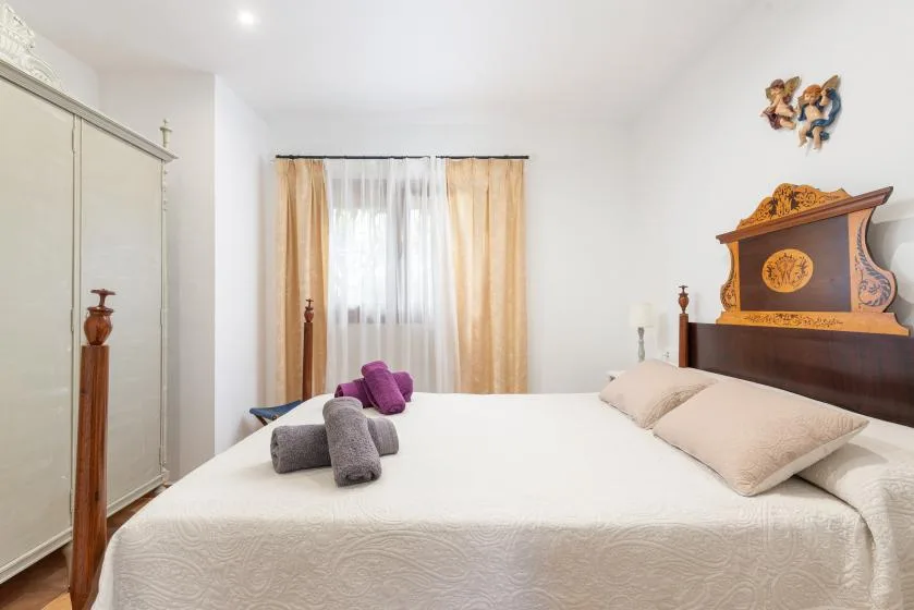 Un dormitorio con una cama, almohadas y una ventana con cortinas.