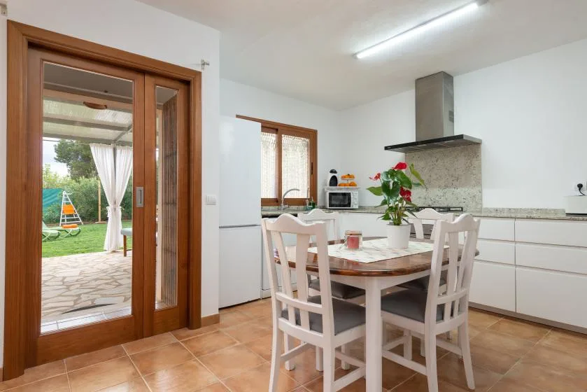Una luminosa zona de comedor con mesa y sillas junto a una cocina.