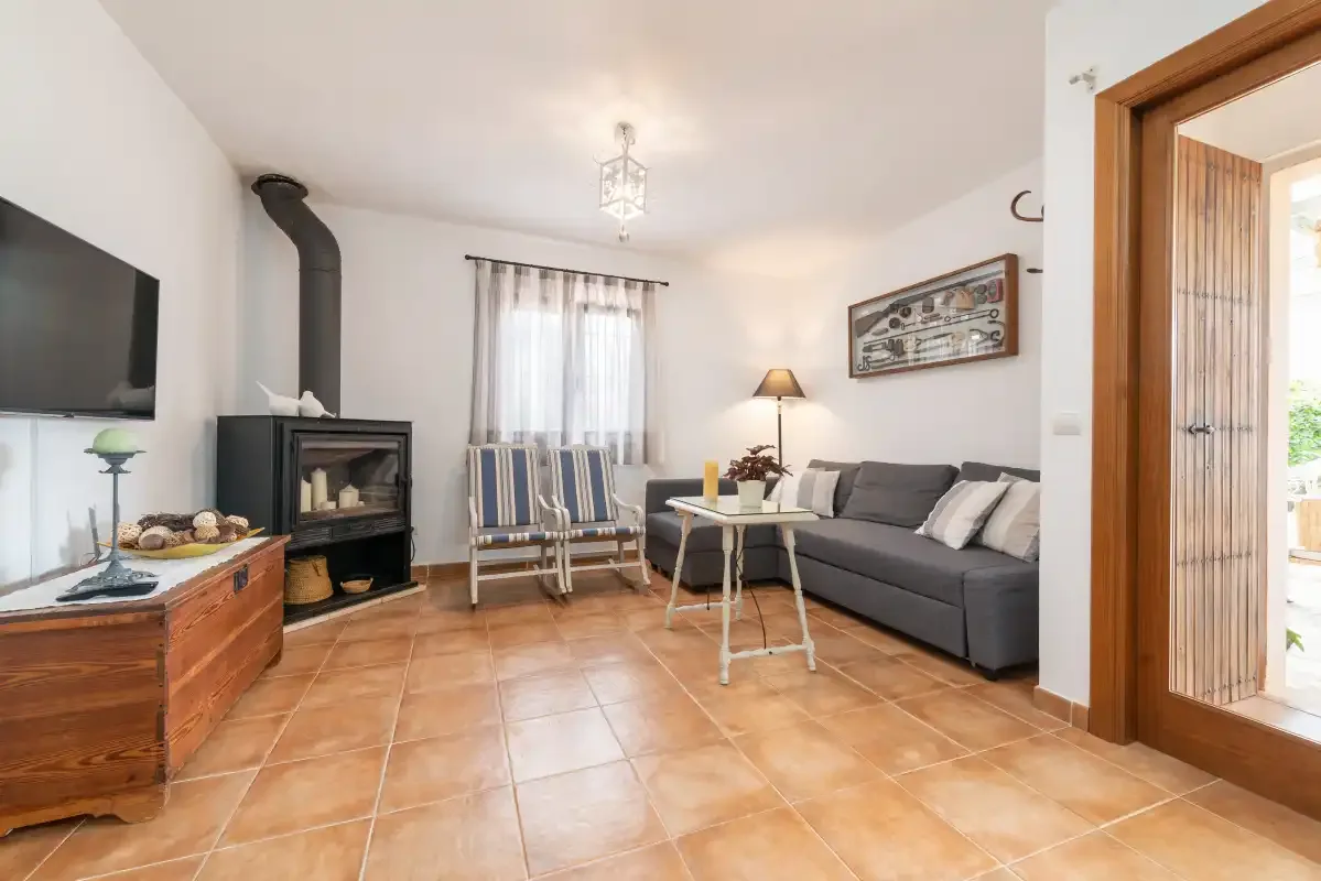 Una sala de estar con chimenea, asientos grises y una mesa pequeña.