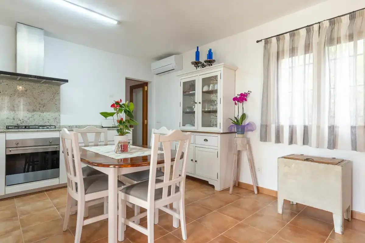 Un comedor con una mesa y sillas junto a una cocina.