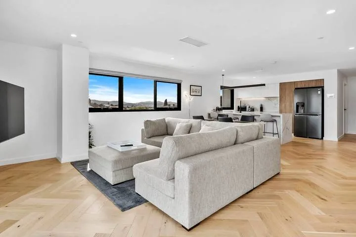 An open-plan living area with light seating and a kitchen in the background.