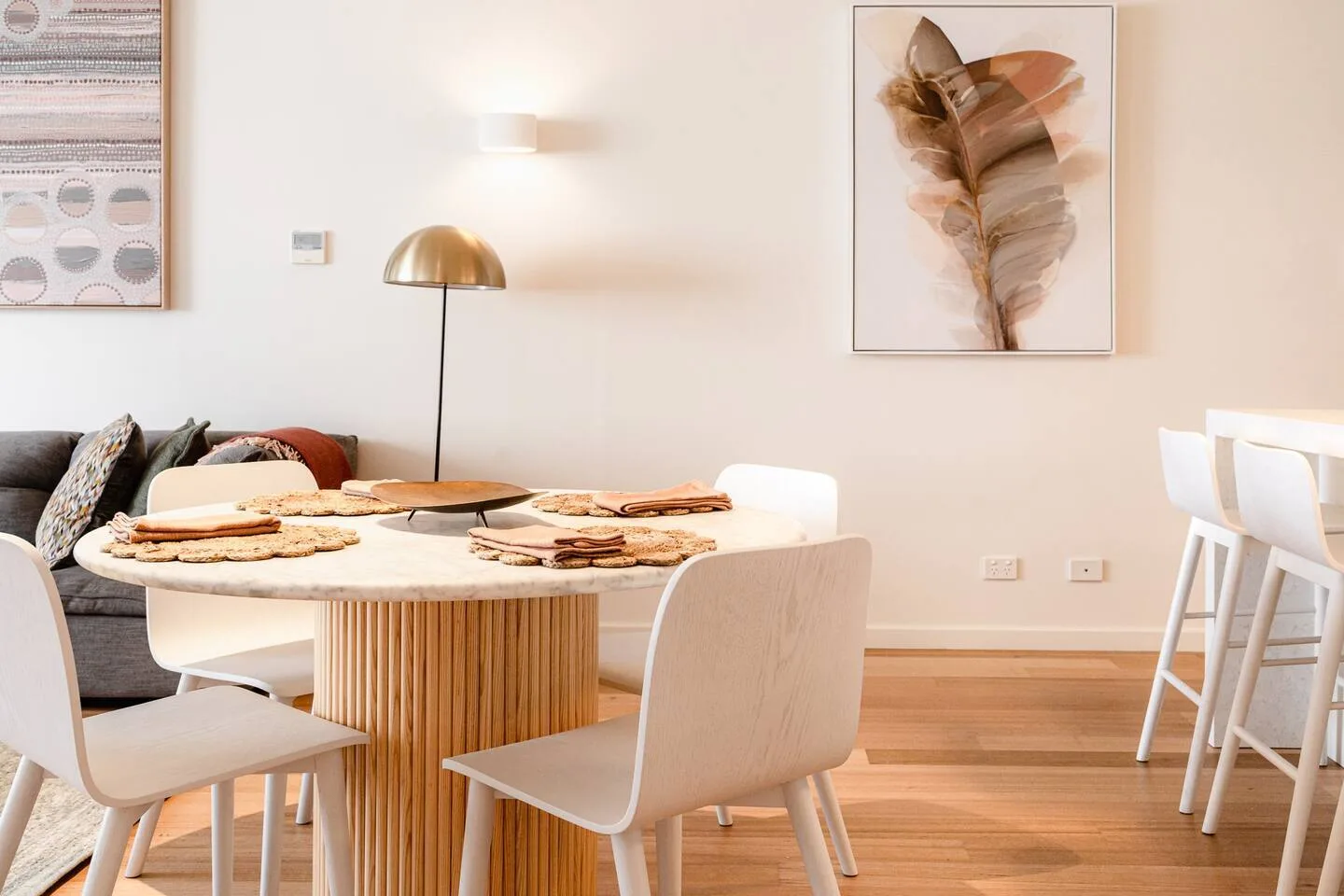 A dining area has a round table and chairs beside a kitchen counter with stools.