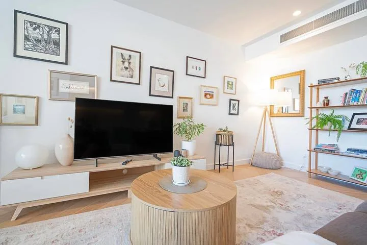 A bright living room with a television, framed artwork, and a round coffee table.