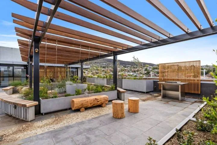 A rooftop patio with pergola beams, raised planters, and a built-in seating area.