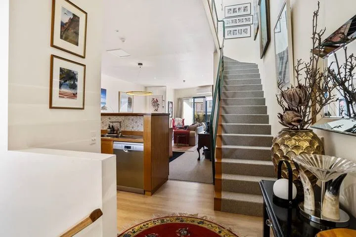 An open-plan living area and kitchen sit beside a staircase.