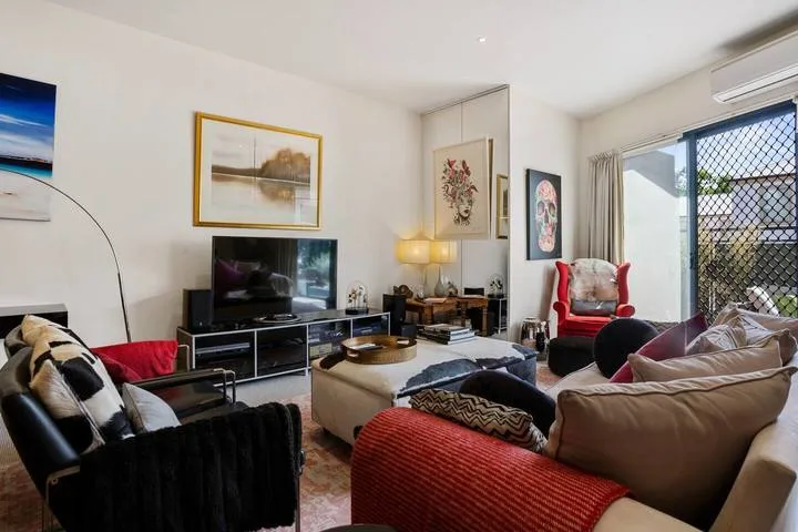 A living room with seating arranged around a coffee table and television.