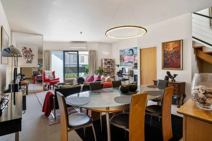 A bright open-plan living and dining area with a large dining table and seating.