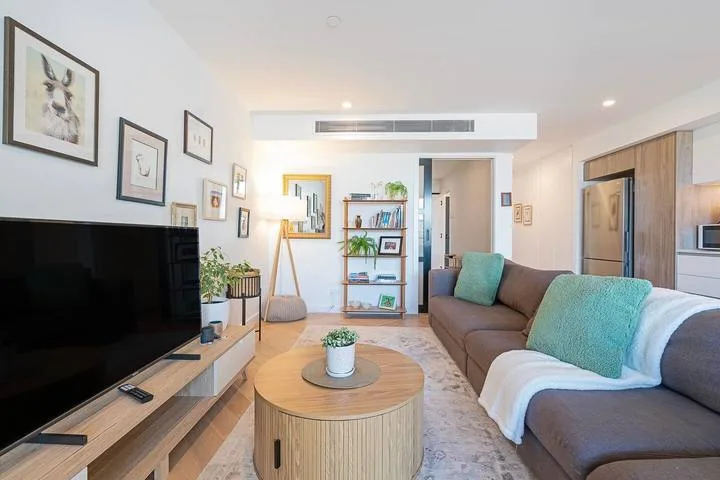 A bright living room with seating, a television, and framed artwork.
