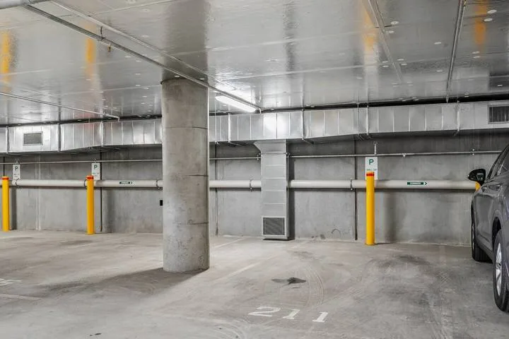 An underground parking garage with concrete pillars and a parked vehicle.