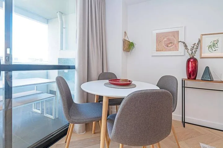 A dining area with a round table and gray seating beside a glass door.